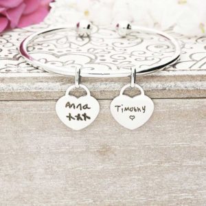 A silver bangle with two silver hearts that can be personalised as you wish