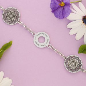 A silver bracelet with silver circle charm with 2 mandala charms