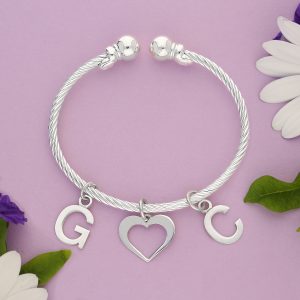 A silver torque lined bangle with a heart and 2 initials