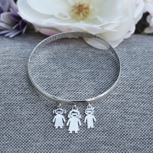 A 6mm wide rounded silver bangle with three charms